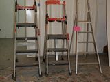 three ladders that are standing in a room with paint on the floor