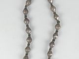 a close up of a necklace with beads on a white surface
