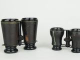 two black binoculars are sitting next to each other on a white surface