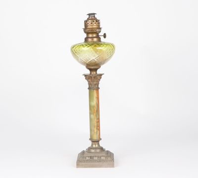 an old fashioned lamp with a green glass shade on it