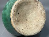a close up of a green vase on a gray surface