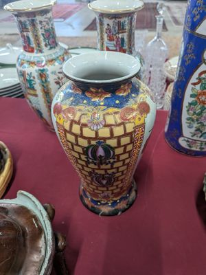 many vases and plates on a table with a red table cloth