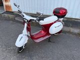 un scooter rouge et blanc garé devant un immeuble