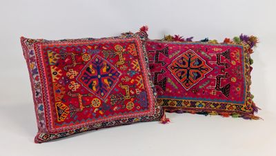 deux coussins aux motifs colorés et ornés de pompons