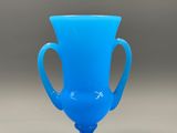 a blue glass vase with a handle on a table
