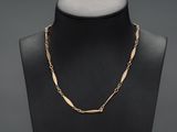 un torse de mannequin noir portant un collier à chaîne dorée