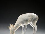 une sculpture blanche représentant un cerf, posée sur un socle transparent