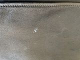 the back of a black purse with a small hole in it