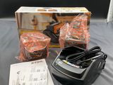 a box of oranges sitting on a bed next to a charger