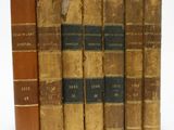 six vieux livres sont alignés sur une surface blanche