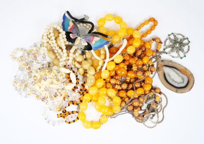 un tas de perles et de colliers de toutes sortes posés sur une surface blanche