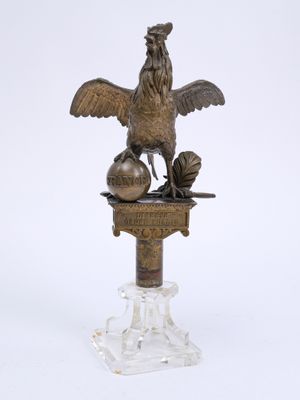 statue d'un coq sur un socle, sur fond blanc