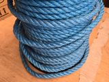 une corde bleue torsadée posée sur une table en bois, avec une boîte en arrière-plan