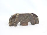 a small carved elephant sitting on a white surface