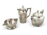 three pieces of silverware including a teapot, sugar bowl, and spoon