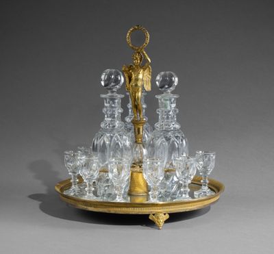 a tray that has a glass and gold plate with a candle holder on it