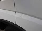 the side of a white van with a hole in the side of it