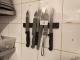 several knives are hanging on a wall in a kitchen