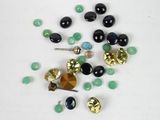some black and green beads and gold bells on a white surface