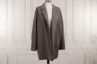 the coat is on a mannequin stand in front of a white wall