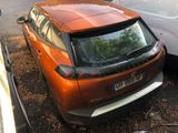 a small orange car parked next to a white van
