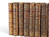 several old books are lined up in a row on a white surface