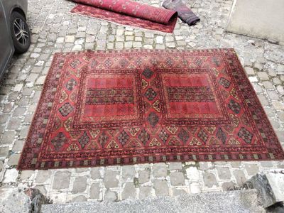 a red rug on the ground next to a car