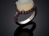 a close up of a ring with a white opal and pink sapphires