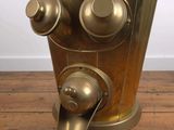 a gold vase with a water fountain inside of it on a wooden floor