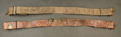 two belts with metal buckles on them on a gray surface