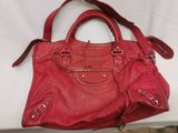 red leather handbag sitting on a white table with a white background