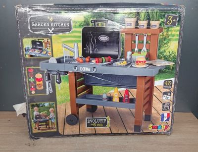 une boîte sur laquelle est posé un petit barbecue miniature, posée sur une table en bois