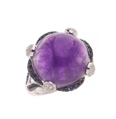 une image représentant une bague ornée d'une pierre violette entourée de saphirs bleus