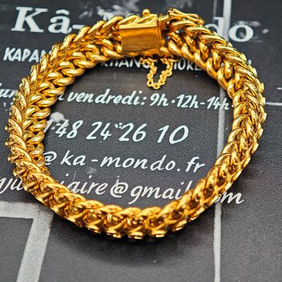 bracelet à chaîne en or orné d'une croix, sur fond noir
