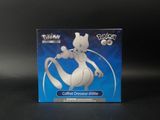 La boîte d'une figurine Pokémon est posée sur une surface noire.