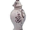 a white vase with a bird on top of it