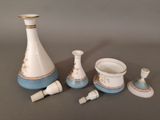 a white and blue vase, a cup, and two cups on a table