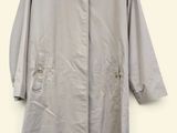 grey trench coat on a hanger against a white wall