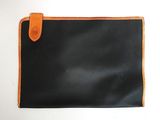 une image représentant un portefeuille noir et orange posé sur une surface blanche