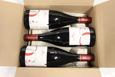 three bottles of wine in a cardboard box on a table