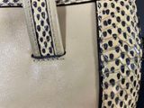 beige and black leopard print handbag on display on a mannequin mannequin mannequin mannequin mannequin mannequin mannequin