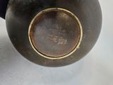 a black vase with a gold rim sitting on a table