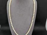un collier de perles blanches sur un mannequin avec un fermoir en or