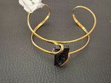 a close up of a gold cuff with a black stone on it