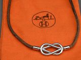 une photo d'un collier orné d'un nœud, posé sur un tissu orange
