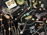 many different necklaces and bracelets laid out on a table