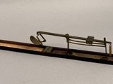 a small metal object on a wooden stand on a white surface