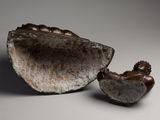 two bronze figurines of a woman and a shell on a gray surface