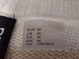 the label of a white sweater with a black label on it