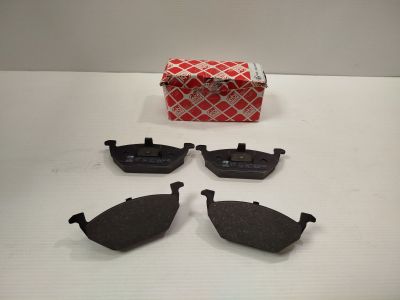 quatre paires de plaquettes de frein et une boîte rouge posée sur une table blanche